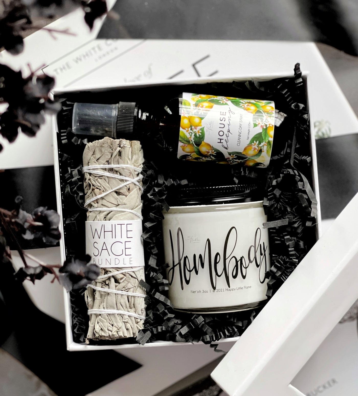 Home Sweet Home gift box containing a white sage smudge stick, a lavender vanilla candle, and a housekeeping spray from Happy Little Flame